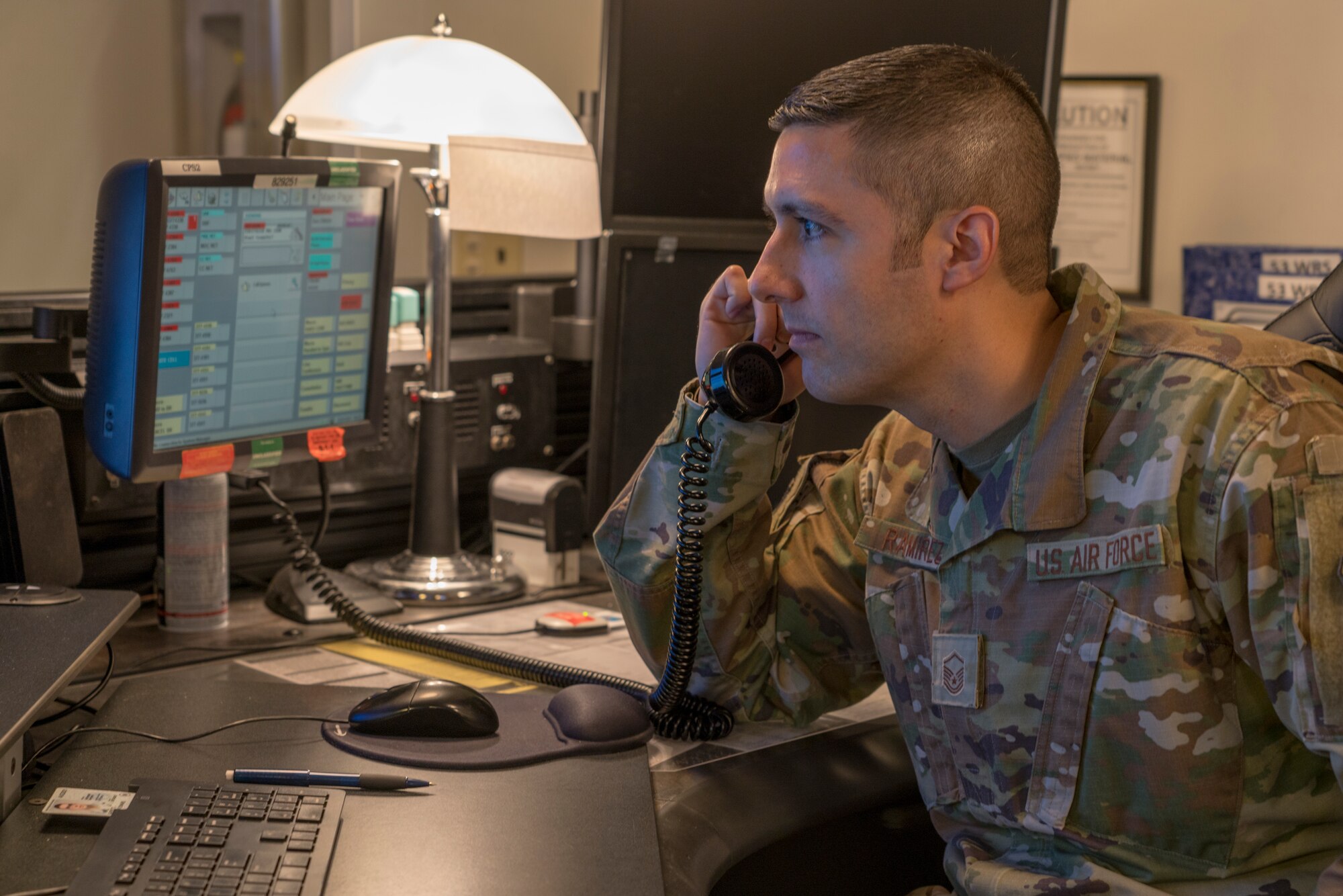 Master Sgt. Carlos Ramirez, 403rd Wing Command Post readiness reporting manager, answers questions about current base operations over the phone at Keesler Air Force Base, Miss., April 11, 2021. The command post manages and performs a multitude of command and control operations that, depending on the call they receive, can vary from minor issues to major incidents. (U.S. Air Force photo by 2nd Lt. Christopher Carranza)