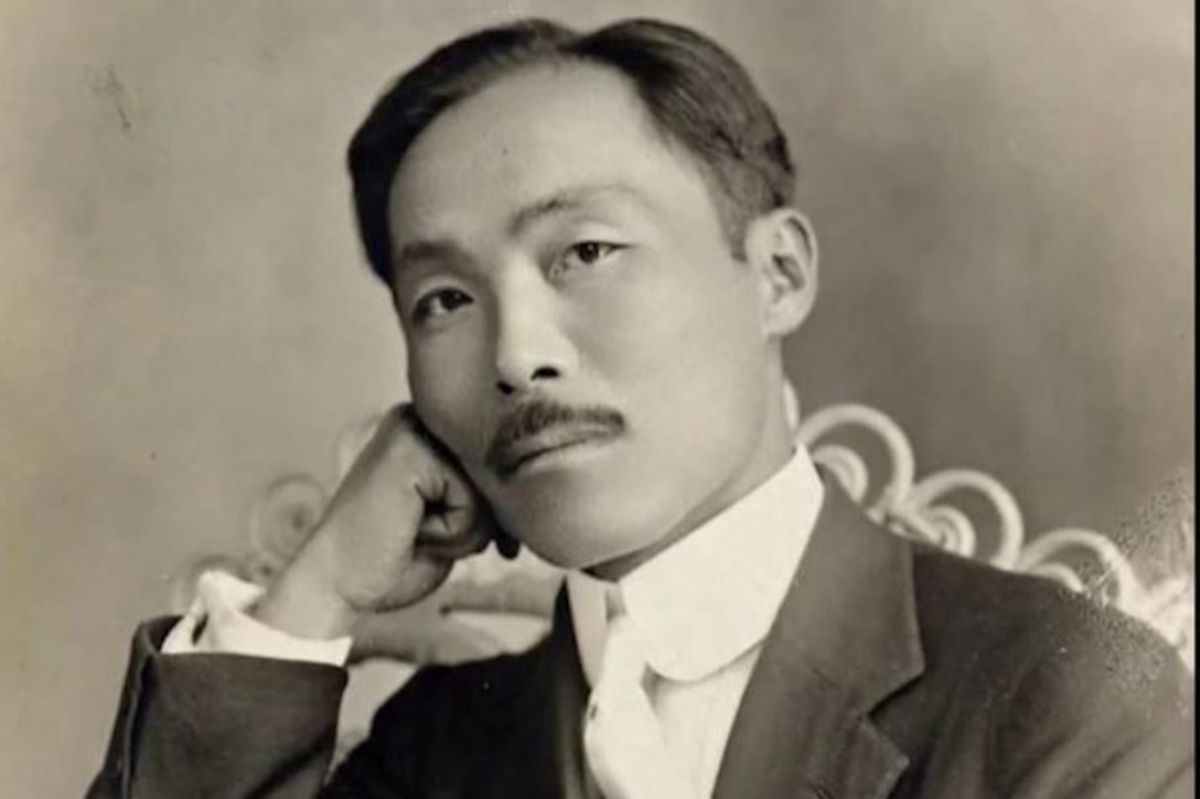 A man in a suit rests poses for an informal picture.