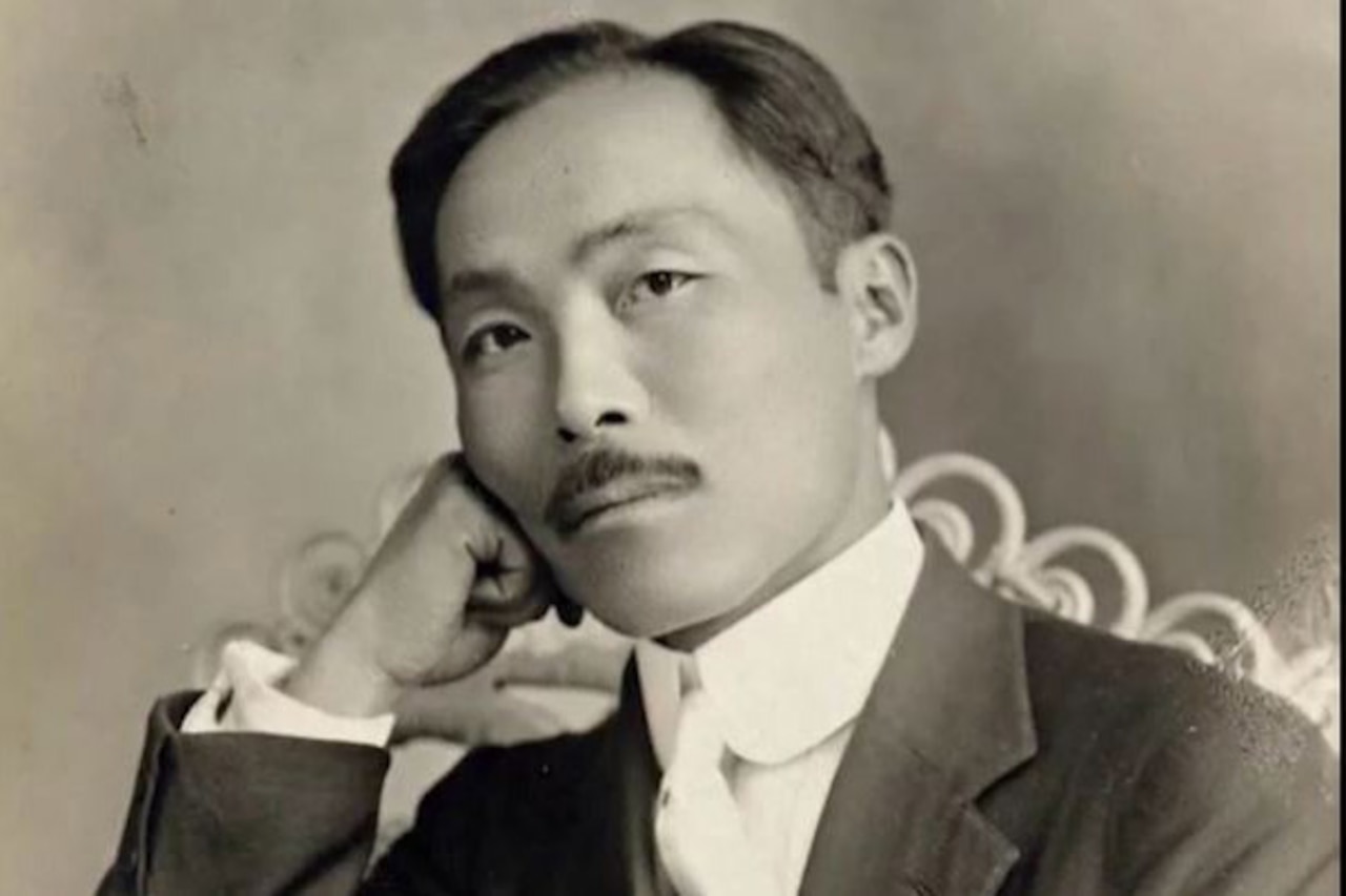 A man in a suit rests poses for an informal picture.