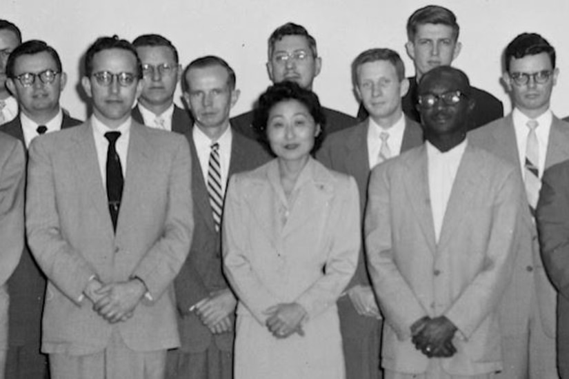 A group of men and one woman, all in business suits, pose for a photo.