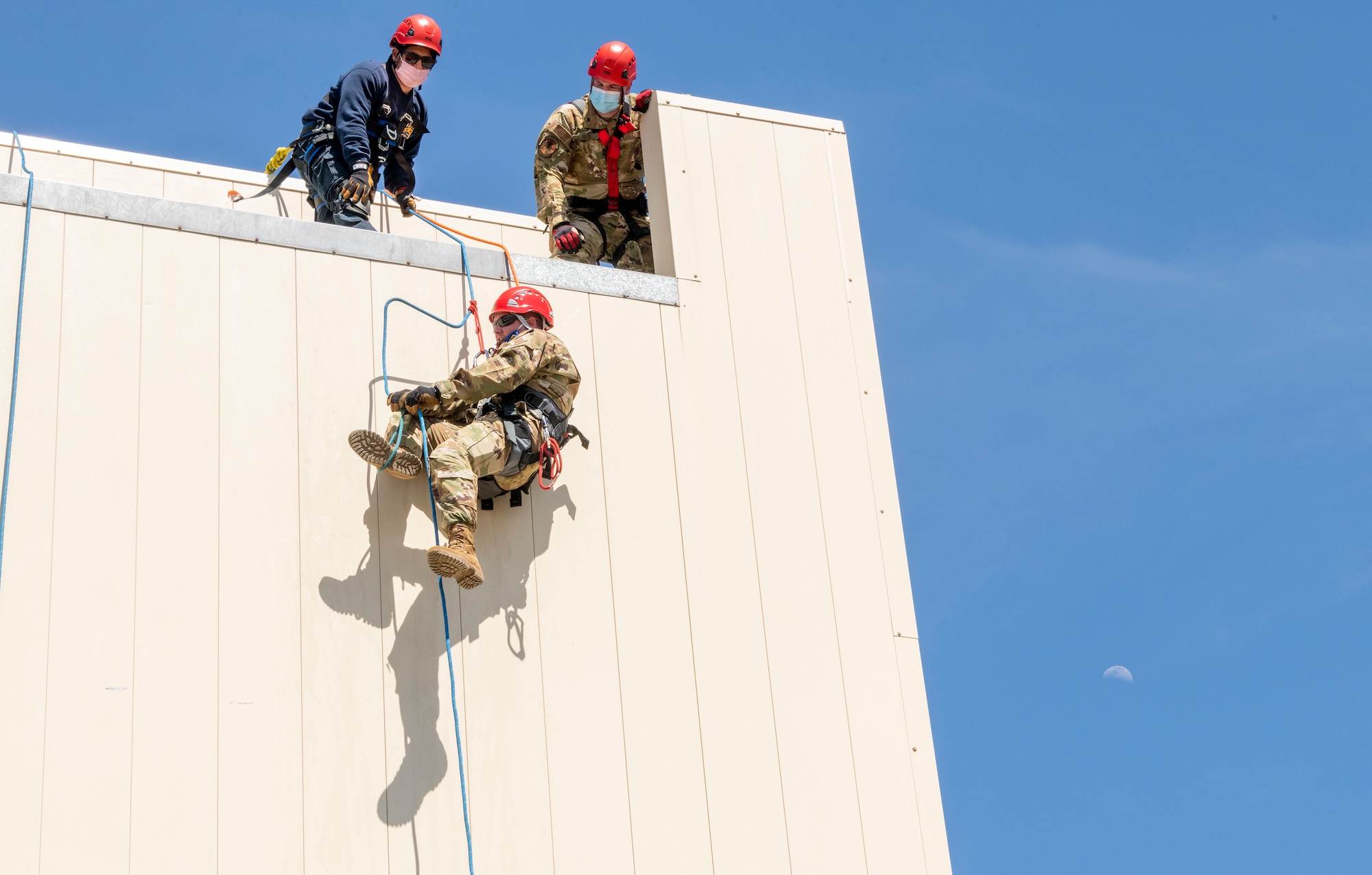 Ricardo Campos, left, and U.S. Air Force Staff Sgt. Justin Rice, 60th Civil Engineer Squadron lead fire fighters, watch as Tech Sgt. Christopher Klingelhoets, 60th CES fire protection crew chief, ascend a structure April 19, 2021, at the Travis Fire and Emergency Services training facility at Travis Air Force Base, California. The training demonstration provided senior leadership with a clear picture of the technical rescue capabilities for multi-story building and confined space rescues conducted by Travis AFB emergency response personnel. (U.S. Air Force photo by Heide Couch)
