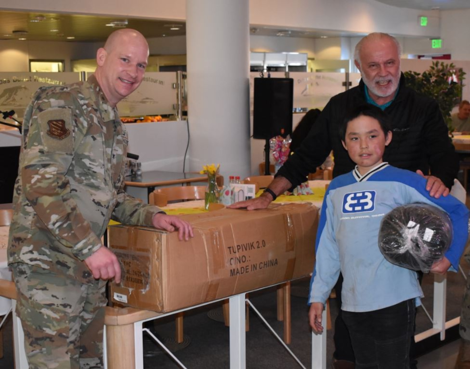 Nuka, middle, 11 years old, poses for a photo with U.S. Air Force Col. David Hanson 821st Air Base Group commander and William Womack, base contract director, after receiving a sled tent as one of the winners of the dogsled races held at North Star Bay, Thule Air Base, Greenland, April 4, 2021. Nuka was the youngest of 17 dog racers participating in Greenlandic Heritage Week and had a time of 25 minutes. The base invited families from local villages to stay and participate in several events that celebrate their cultural traditions. (U.S. Space Force photo by Lt. Col. Christopher Ivarone)