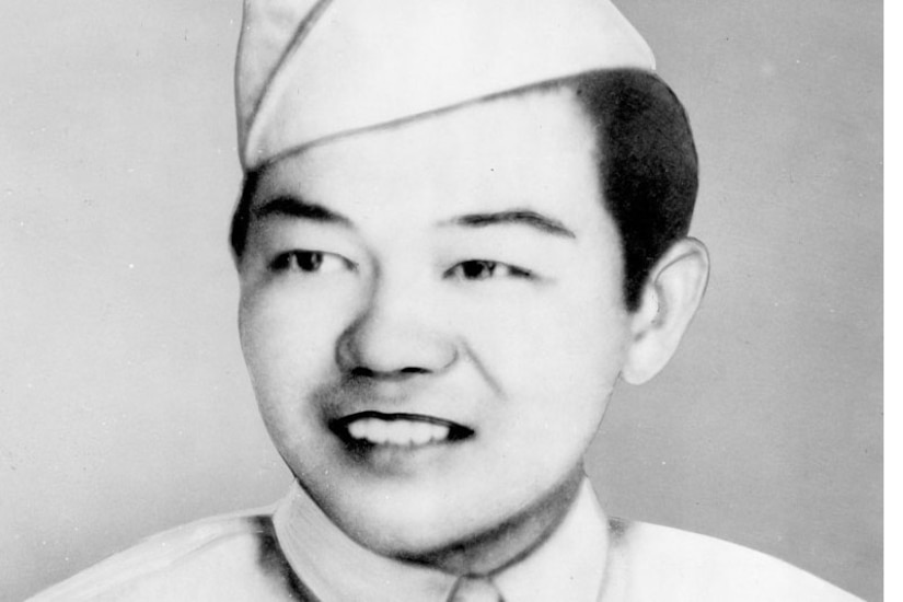 A man in uniform and cap smiles.