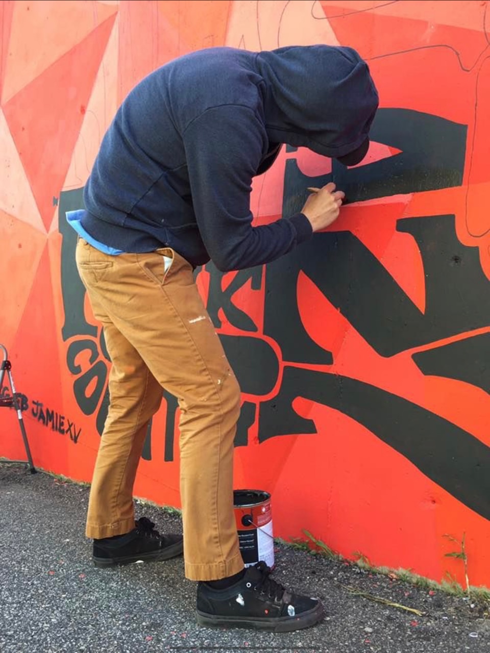 A sailor in civilian clothes paints a mural.