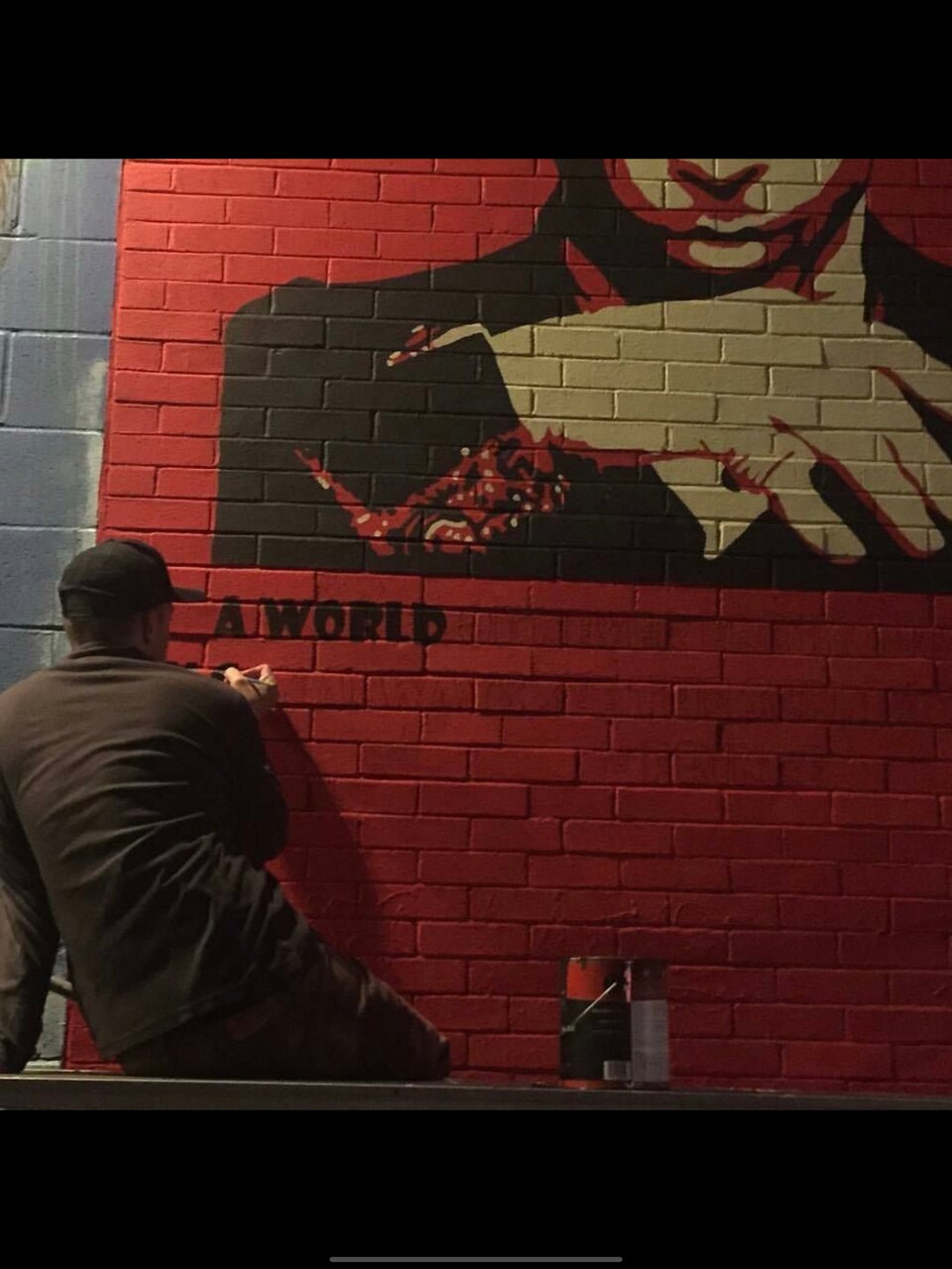 A sailor in civilian clothes paints a mural.