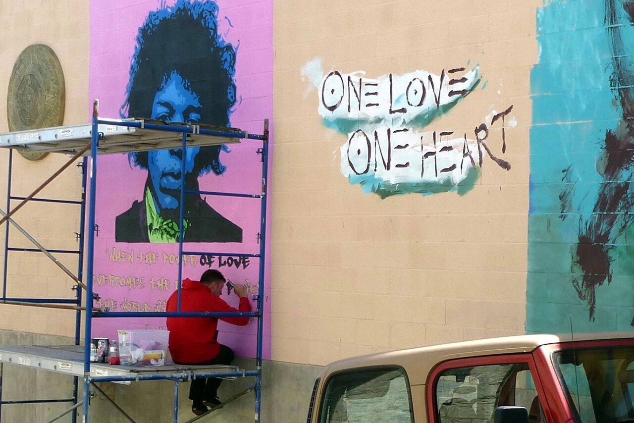 A sailor in civilian clothes paints a mural.