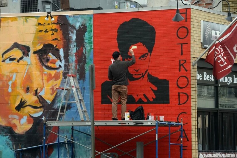 A sailor in civilian clothes paints a mural.