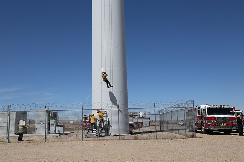Eric Keck, firefighter/paramedic with Fire and Emergency Services, rappels 230 feet from a wind turbine as part of the Technical Rope Rescue training held aboard Marine Corps Logistics Base Barstow, California, April 15. Captain Tim Yonta, prepares to guide Keck safely to his feet once he reaches the platform below. The training was conducted by Tech Rescue Trainers, Inc. as part of a comprehensive series of technical rescue courses.