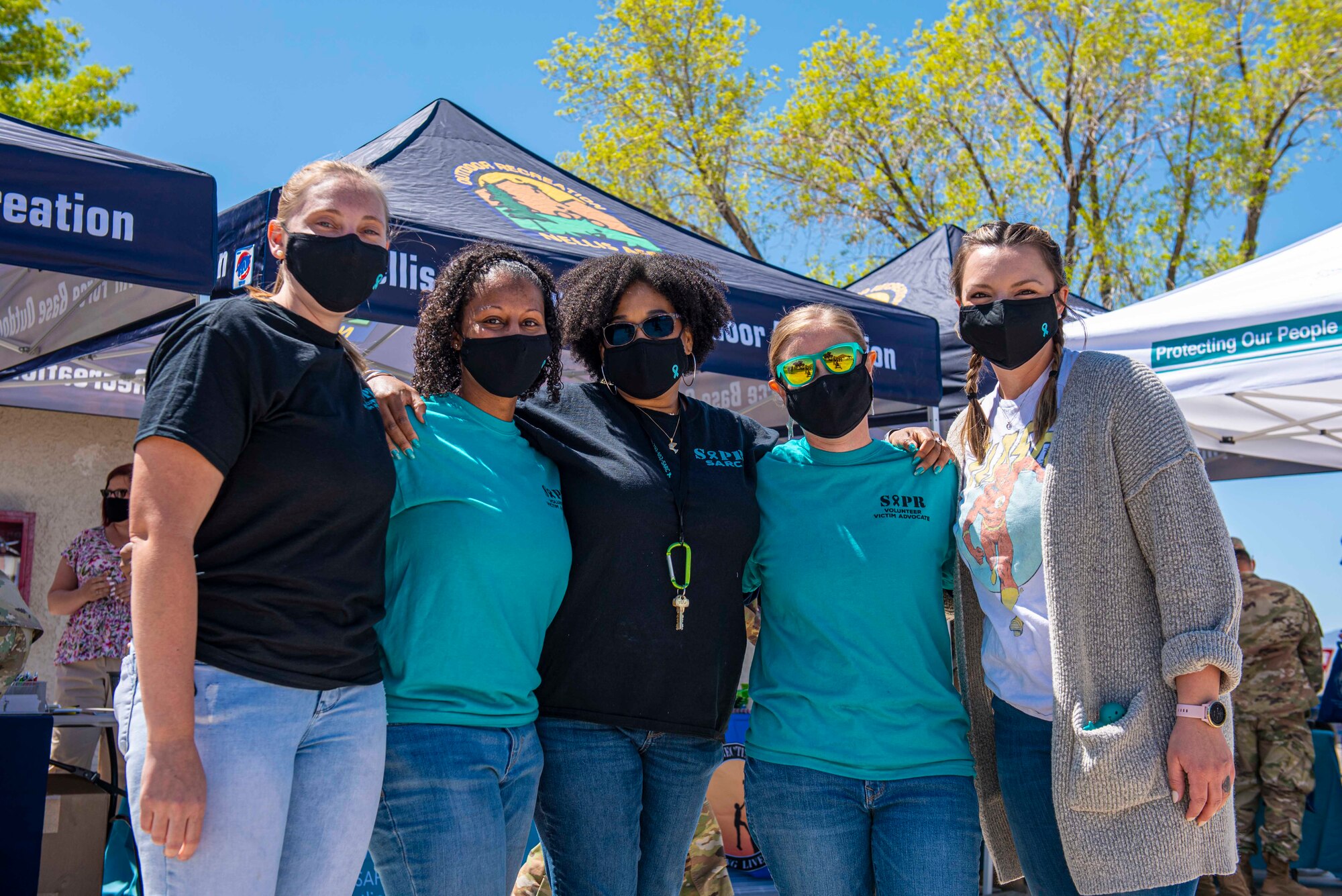 Group of five women wearing Sexual Assault Prevention and Response t-shirts pose arm in arm for a photo.