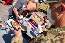Male Airman puts barbecue sauce on his pulled pork sandwich.