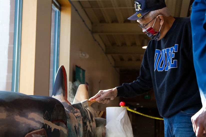 George Bennett restores the 11.5-foot honor pole that sits in front of the Alaska National Guard armory April 17, 2021, on Joint Base Elmendorf-Richardson after 12 years since originally carving it with his son. The pole was originally built in Sitka and serves as a monument dedicated to the profound contributions of the Alaska Natives to the safety and heritage of the state in the past and present. (U.S. Army National Guard photo by Spc. Grace Nechanicky)