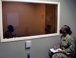 Petty Officer 2nd Class Ebiye Osadare (far right), a Navy instructor for the METC Behavioral Health Technician program, monitors a mock counseling session from behind the glass between BHT students Airman Frederick Hall (left) and Seaman Chery Gonzales-Polanco (right).