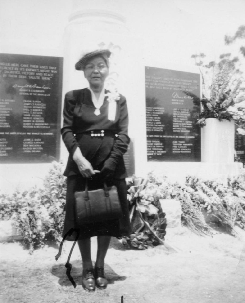 A woman wears a medal on her neck while standing in front of a monument.