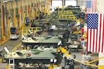 Large building at Marine Depot Maintenance Command, Barstow, California, shows mechanics performing maintenance on a variety of military vehicles.