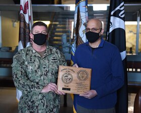 GREAT LAKES, Ill. (Feb. 10, 2021) During an award ceremony at Training Support Center (TSC) Great Lakes, Commanding Officer Capt. Pat Sutton presents Concepcion Natal with a plaque for being TSC’s Junior Civilian of the Year. He was recognized for superior performance with emphasis on outstanding achievements and initiative in performance in the Information Technology (N6) department. (U.S. Navy photo by Matt Mogle/Released)