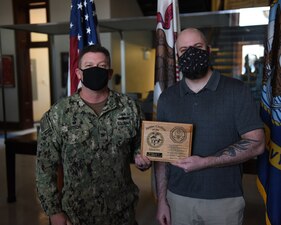 GREAT LAKES, Ill. (Feb. 10, 2021) During an award ceremony Training Support Center (TSC) Great Lakes Commanding Officer Capt. Pat Sutton presents Anthony Bellomo, computer assistant in the Information Technology Office (N6), with a plaque for being awarded TSC’s Junior Civilian of the Quarter, 4th Quarter. He received the award for demonstrating exceptional attention to detail and initiative, as a member of the Cyber Security Workforce Team. He flawlessly managed the System Authorization Access Request Program for the command and five Learning Sites.  (U.S. Navy photo by Matt Mogle/Released)