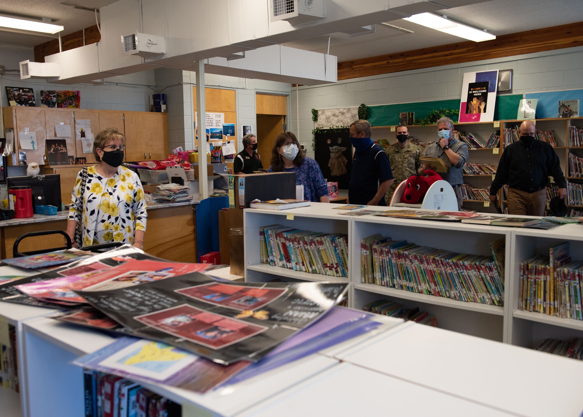 Seven people enter and browse the school library.