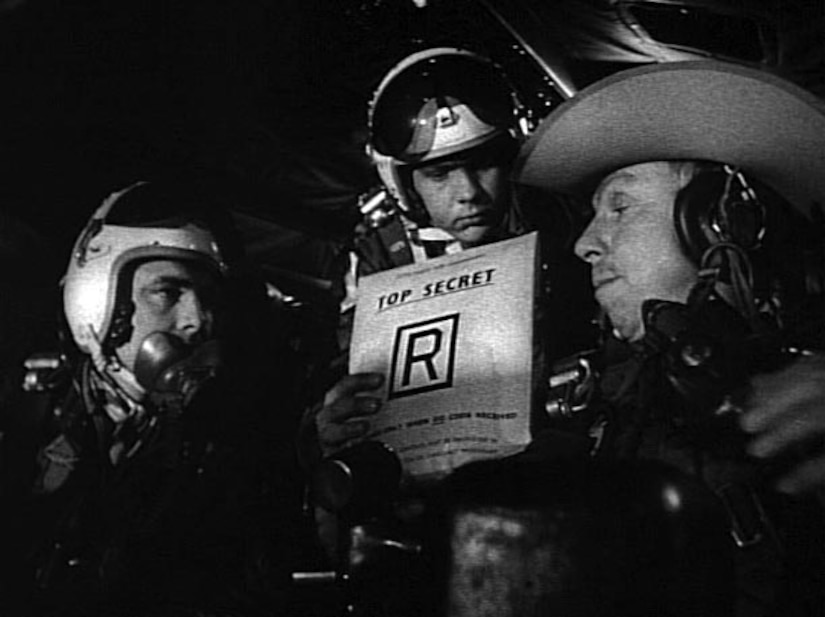 Men dressed as military members talk on a movie set.