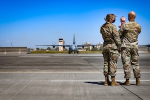 Staff Sgt. Ryann Holzapfel, 374th Airlift Wing Public Affairs craftsman, left, and her husband Staff Sgt. Brendan Miller, Armed Forces Network Tokyo broadcaster, stand on the Yokota flight line with their six-month-old son at Yokota Air Base, Japan, April 26, 2021.