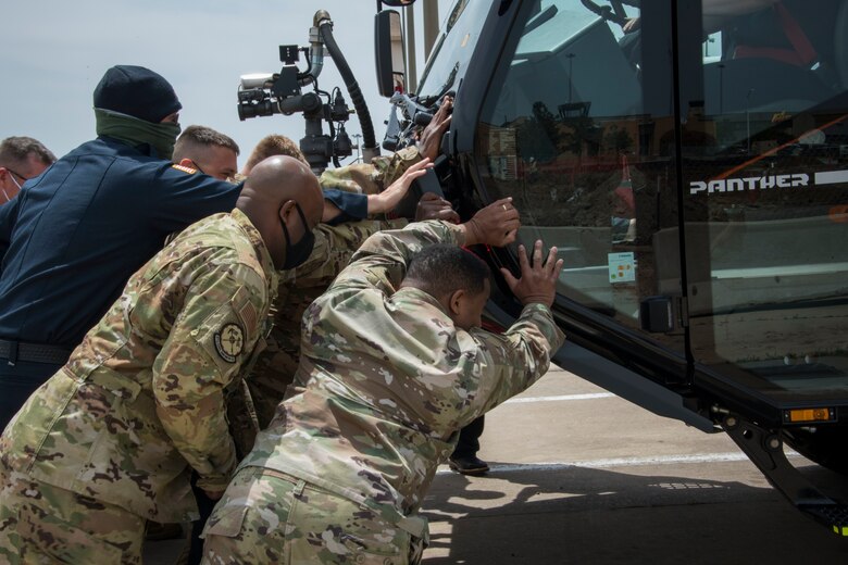 Airmen “house” a new fire truck, April 26, 2021, at Altus Air Force Base, Oklahoma. The “housing” tradition stems from the 1830s when fire companies used horse-drawn fire carts that could not be backed into the fire house, causing firemen and local community members to manually push the fire cart into the fire house. (U.S. Air Force photo by Airman 1st Class Amanda Lovelace)