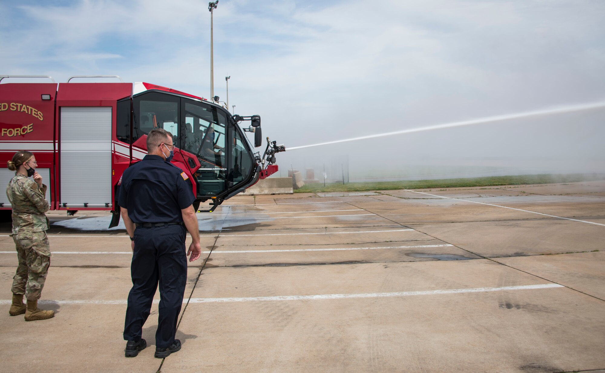 Airmen watch as the new base fire truck sprays water, April 26, 2021, at Altus Air Force Base, Oklahoma. The fire truck can hold up to 3,000 pounds of water. (U.S. Air Force photo by Airman 1st Class Amanda Lovelace)