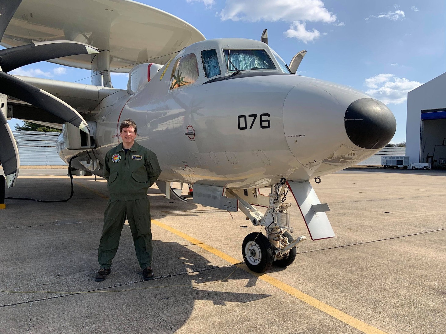 Lt. Cmdr. Brian Abbott poses in front of an aircraft for a photo.
