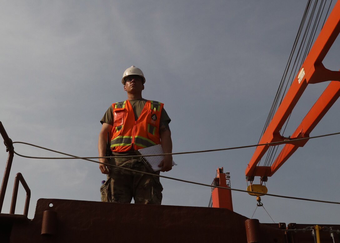 Army Reserve Staff Sgt. Armando Ramirez, deployed to Kuwait with the Lancaster, Pennsylvania, based 1185th Deployment and Distribution Support Battalion, watches the April 24, 2021 onload of shipping containers of ammunition aboard the Military Sealift Command container ship Sagamore at Kuwait's Port Shuaiba. Ramirez, who is a civilian fork truck driver at the Port of Long Beach, California, said he focused on safely loading the containers to protect the ship and its crew.