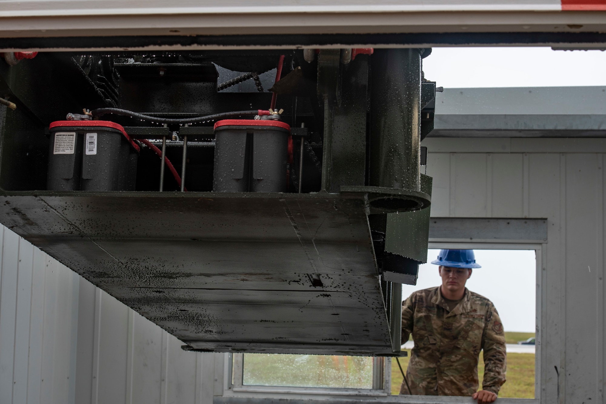 U.S. Air Force Senior Airman Cody Chenowith, 36th Civil Engineer Squadron pavement and equipment operations journeyman, watches as a crane lowers the new Barrier Arresting Kit into place on the flight line at Andersen Air Force Base, Guam, April 26, 2021.
