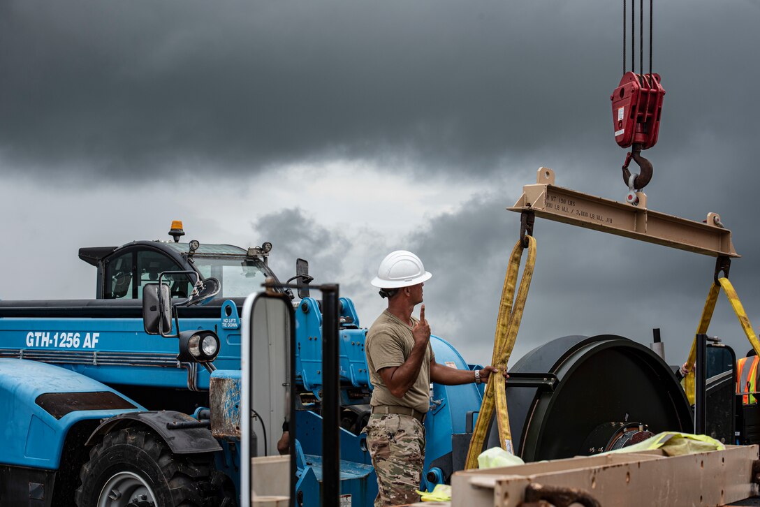 Master Sgt. Jeremy Lawson, 36th Civil Engineer Squadron heavy repair section chief, signals to a crane operator to lift a new Barrier Arresting Kit on the flight line at Andersen Air Force Base, Guam, April 26, 2021. According to the technical order, BAK-12s are overhauled and replaced every ten years. The BAK-12 feeds a cable across the flight line and, in the case of an in-flight emergency, acts as a mechanical barrier that rapidly decelerates a landing aircraft.