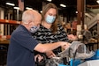 Photo of a woman and a man are in a warehouse area looking at documentation.