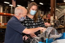 Photo of a woman and a man are in a warehouse area looking at documentation.