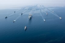 210421-A-BD272-0073 ARABIAN GULF (April 21, 2021) - A multinalional group of mine countermeasure ships from the French Marine Nationale, UK Royal Navy, U.S. Navy and a MH-53E Sea Dragon helicopter, attached to the “Blackhawks” of Helicopter Mine Countermeasures Squadron (HM-15), operate in formation during exercise Artemis Trident 21 in the Arabian Gulf, April 21. Artemis Trident 21 is a multilateral mine countermeasures exercise between the UK, Australia, France and U.S., designed to enhance mutual interoperability and capabilities in mine hunting and clearance, maritime security and dive operations, allowing participating naval forces to effectively develop the necessary skills to address threats to regional security, freedom of navigation and the free flow of commerce. (U.S. Army photo by Spc. Theoren Neal)