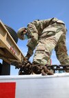 U.S. Army Spc. Israel Navarro, assigned to the 268th Cargo Transfer Company out of Puerto Rico, removes tie-down chains from a tractor trailer during exercise Guardian Response 21 (GR21) on Camper Atterbury, Indiana, April 27, 2021.