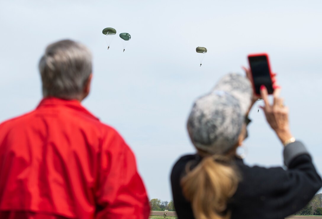 Spectators watch as members of a WWII airborne demonstration team participate in a mass parachute jump during a 100th birthday celebration for WWII veteran Jim “Pee Wee” Martin, April 23, 2021, in Xenia, Ohio. Martin served as a paratrooper assigned to 101st Airborne Division, 506th Infantry Regiment, G Company, out of Fort Campbell, Kentucky. (U.S. Air Force photo by Wesley Farnsworth)