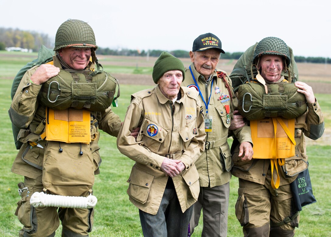 WWII airborne demonstration team members walk with WWII veterans, Dan McBride, center left, and Jim “Pee Wee” Martin, center right, as they exit the drop zone during a 100th birthday celebration held in Martin’s honor, April 23, 2021, in Xenia, Ohio. Both McBride and Martin, served as paratroopers assigned to 101st Airborne Division out of Fort Campbell, Kentucky. (U.S. Air Force photo by Wesley Farnsworth)