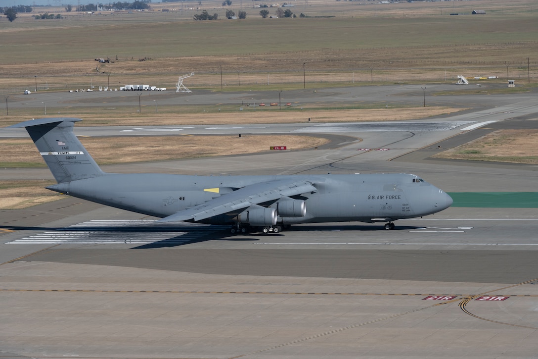 A large military aircraft moves down a runway.