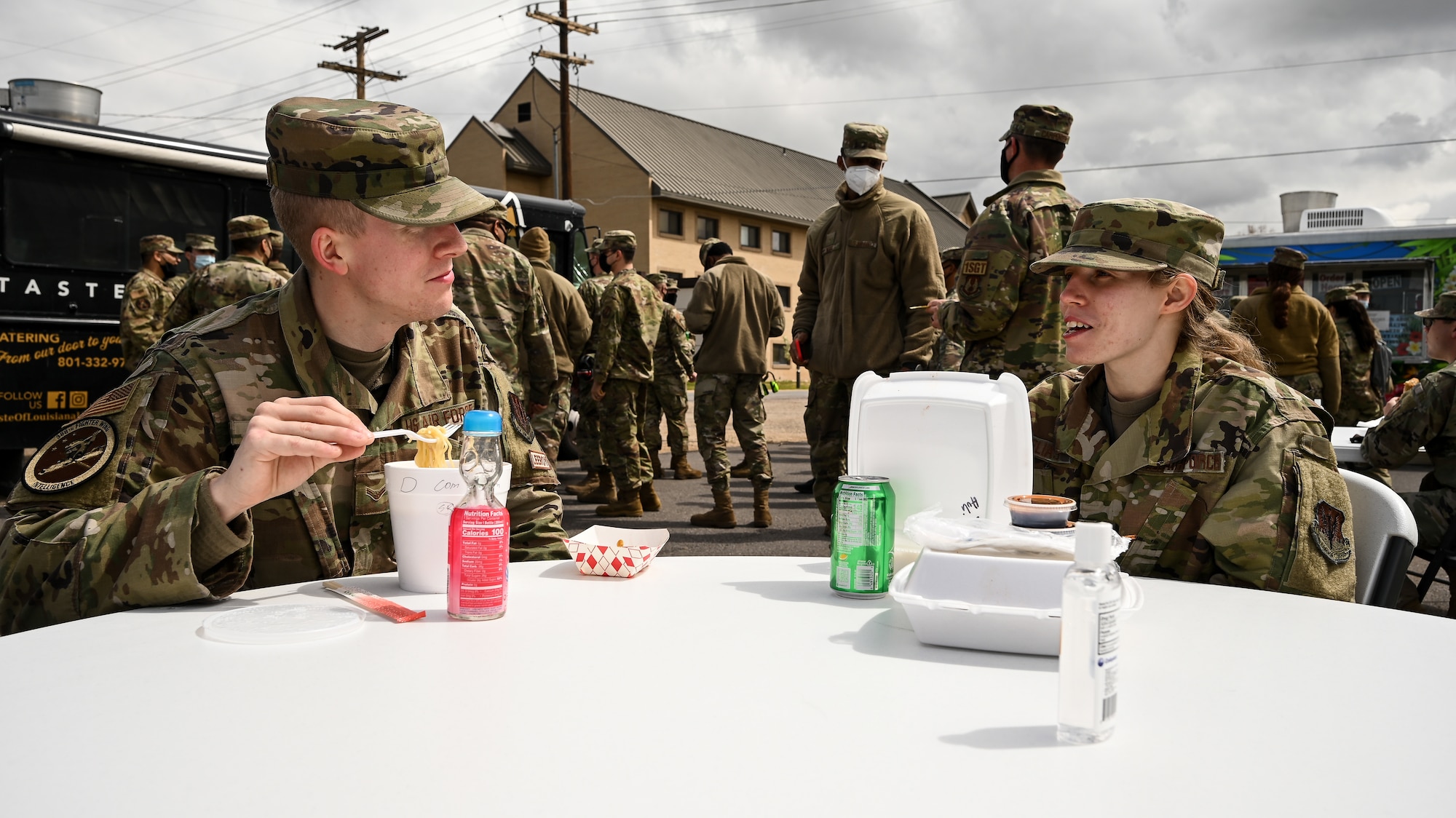 Two Airmen sitting at a table talking and eating.