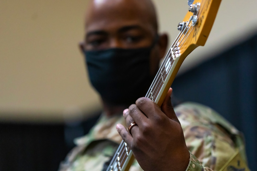 A soldier plays a bass guitar.
