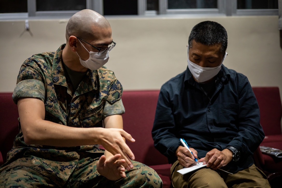 A U.S. Marine teaches English to an Okinawa resident during the English discussion class at the chapel on Marine Corps Air Station Futenma (MCAS), Okinawa, Japan, March 16, 2021. The Futenma Chapel English discussion provides U.S. Marines and Okinawa residents with an opportunity to learn each other's languages and share their cultures. The discussion is held every Tuesday at the MCAS Futenma Chapel at 6:30 p.m. (U.S. Marine Corps photo by Cpl. Terry Wong)