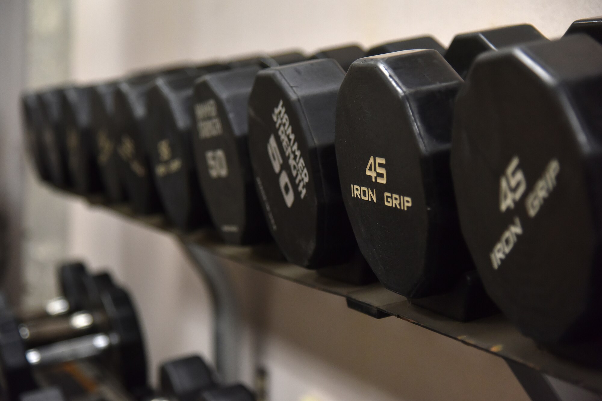 Free weights sit on a rack inside the 35th Fighter Squadron clinic at Kunsan Air Base, Republic of Korea, April 5, 2021. The 8th Operations Group incorporated athletic trainers and a licensed massage therapist within the 35th and 80th Fighter Squadrons as part a program known as Optimizing the Human Weapon System. The program was created to reduce the frequency and severity of neck and back injuries, reduce duty time lost, improve quality of life, enhance readiness, and support fighter aircrew retention.  (U.S. Air Force photo by Senior Airman Suzie Plotnikov)