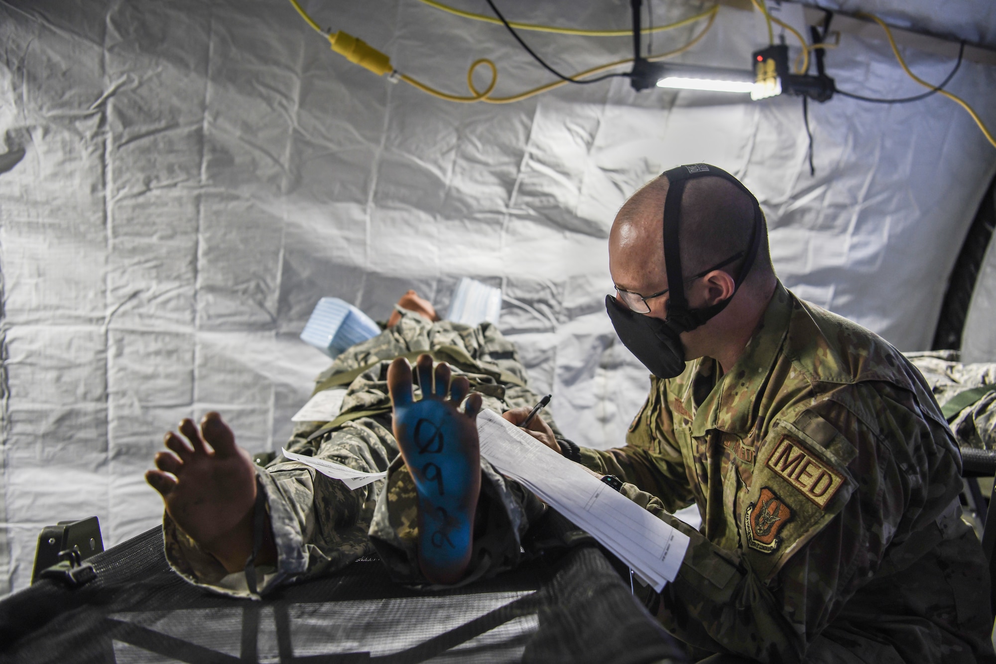 First Lieutenant Tyler Trease, 445th Aeromedical Staging Squadron clinical nurse and officer in-charge of exercise planning and safety, reviews a patient’s medical documentation during Ultimate Caduceus training exercise April 28, 2021.  U.S. Transportation Command (USTRANSCOM) began the week-long aeromedical and global patient movement exercise April 26. Approximately 250 personnel including members of the 445th Airlift Wing and the 88th Air Base Wing participated in the field training exercise. The exercise simulates bringing in injured troops from overseas, triaging them to Wright-Patterson Air Force Base and then moving them to longer-term and advanced care centers known as Federal Coordinating Centers (FCC).  (U.S. Air Force photo/Master Sgt. Patrick O'Reilly)