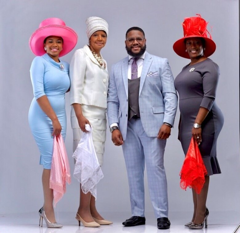 Alexander Harper stands next to models wearing some of his hat creations.