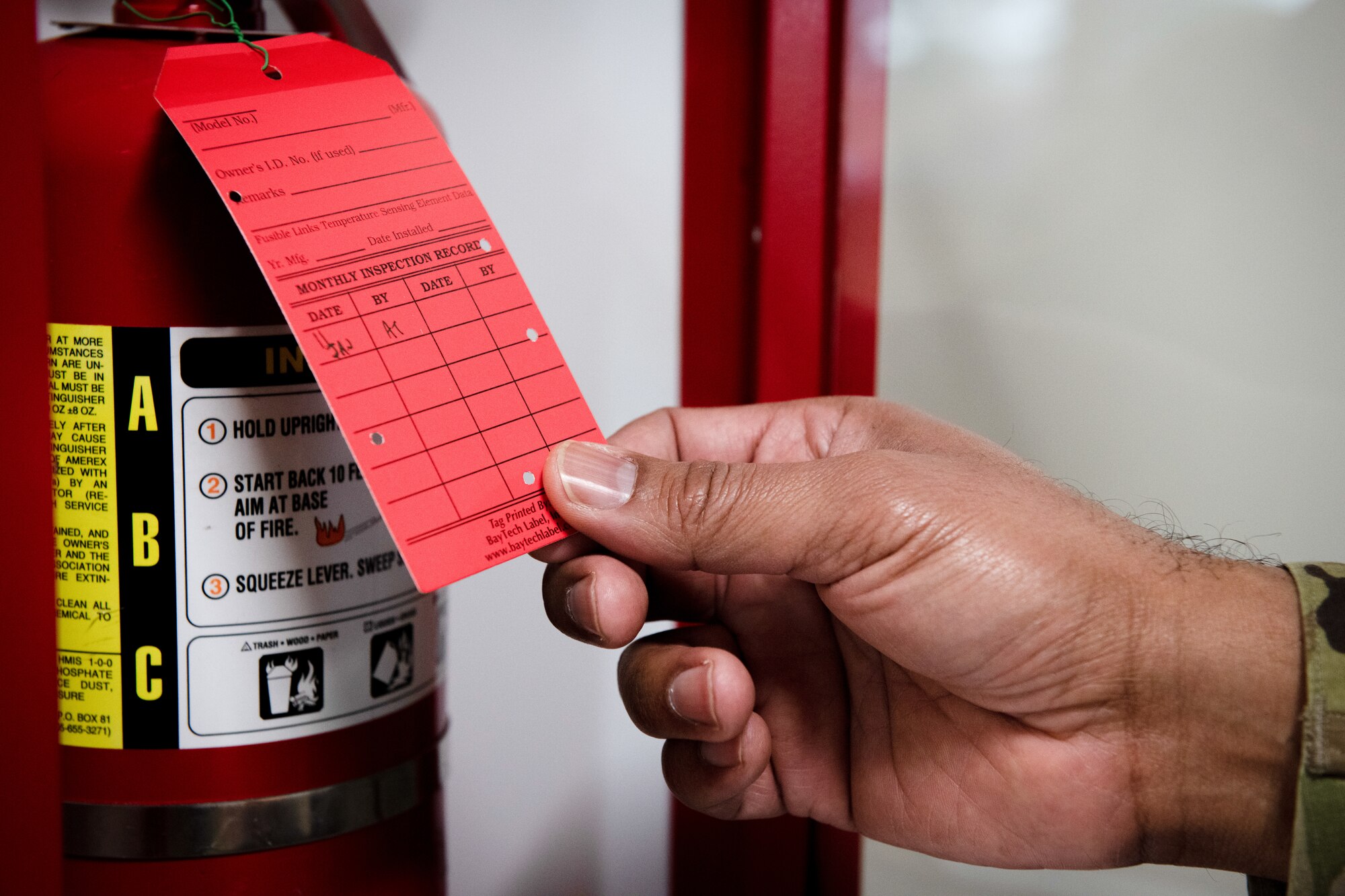 Man holds tag on fire extinguisher.
