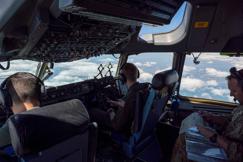 From the left, Capt. Stephen Tice and 1st Lt. Forrest Doss, both 3rd Airlift Squadron pilots, fly a C-17 Globemaster III during a local training flight while Maj. James Johnson, 3rd AS pilot, reviews and discusses a flight plan map over Ohio, April 22, 2021. The 3rd AS trains to support global engagement through direct delivery of critical theater assets and to ensure combat readiness of Air Mobility Command C-17 aircrews. (U.S. Air Force photo by Airman 1st Class Faith Schaefer)