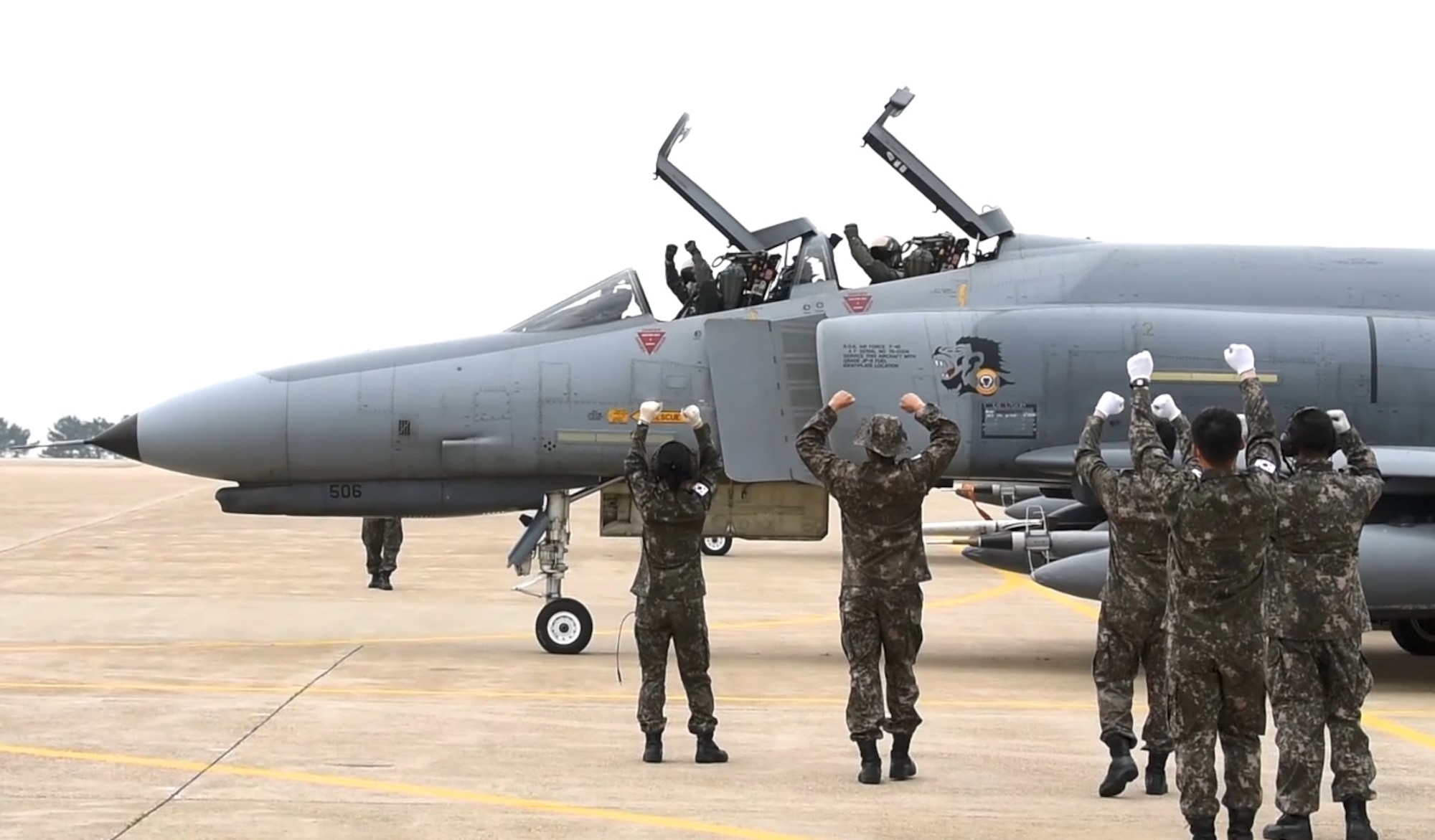 An F-4 Phantom 2 starts to taxi, both ground crew and pilots give a victory sign.