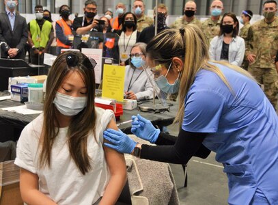 Cassie Huang, 28, of New York receives her first Pfizer vaccination from nurse Raquel Calderon April 26, 2021, marking the 500,000th vaccine administered at the Jacob Javits Center mass vaccination site. More than 3,180 members of the New York Army and Air National Guard, the New York Naval Militia and the New York Guard are supporting the multi-agency response to COVID-19 at 24 vaccination sites and other locations across New York.