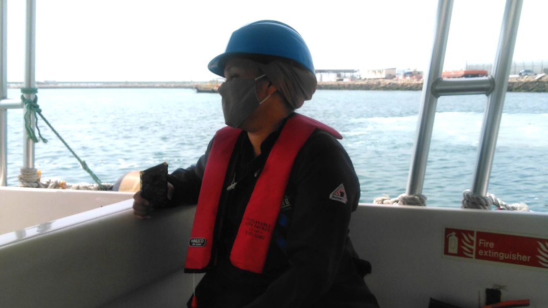 A women in overalls rides in a boat