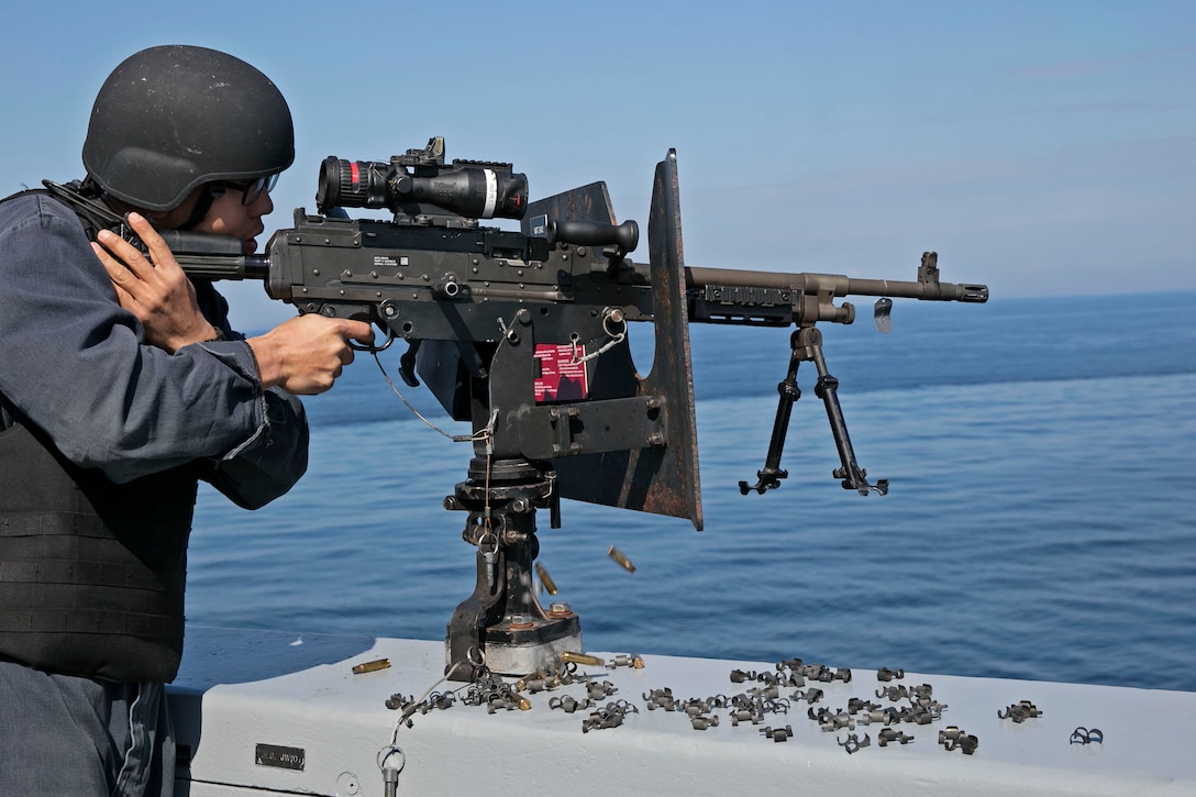 A sailor aims his machine gun.