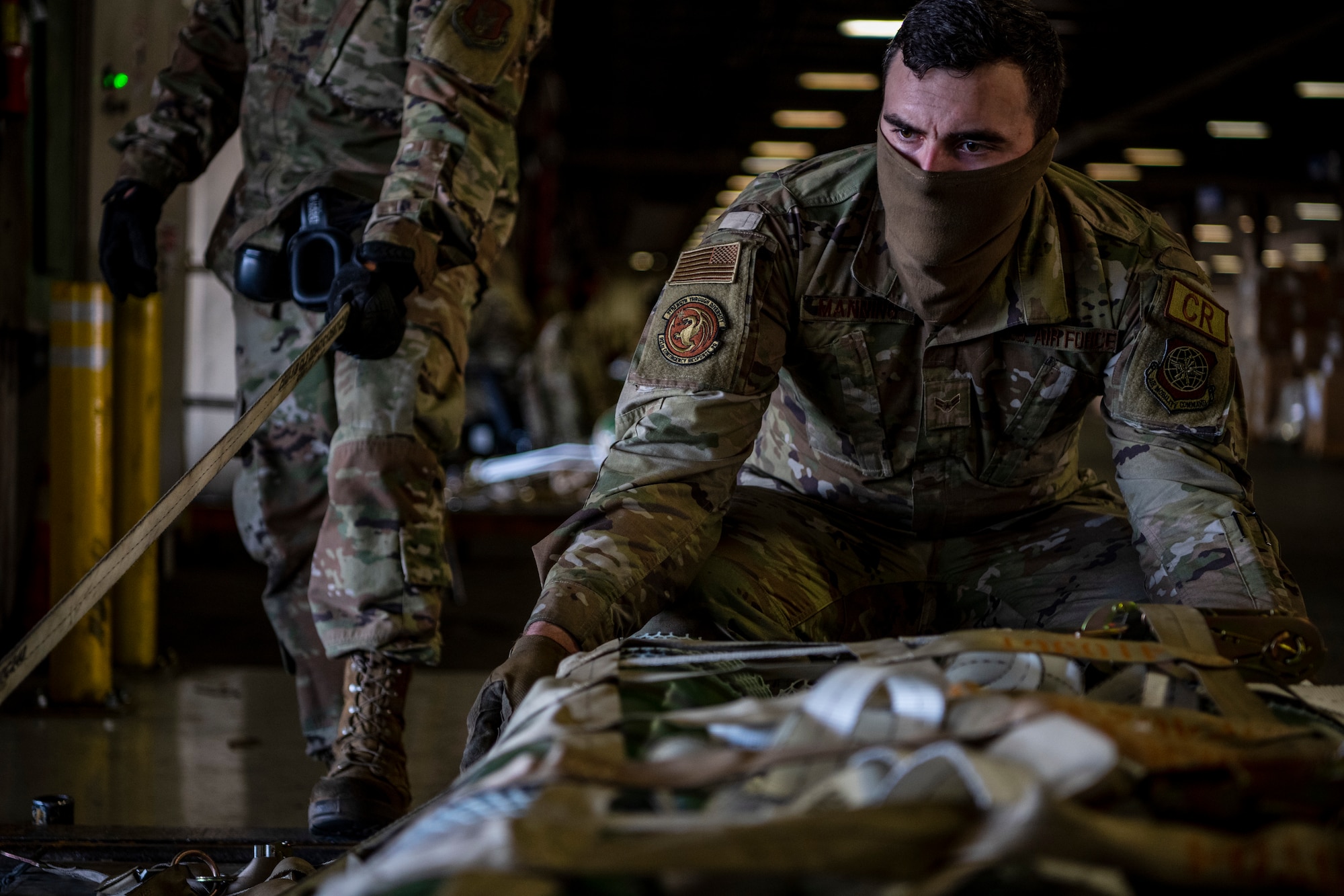 A man is seen securing straps to oxygen cylinders to a pallet.