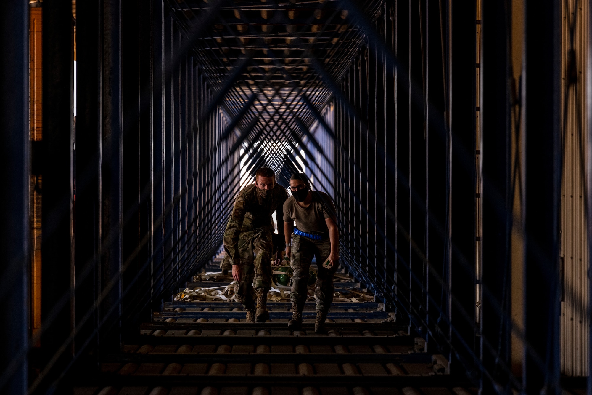 A man and woman walk down a long triangular-shaped hall.